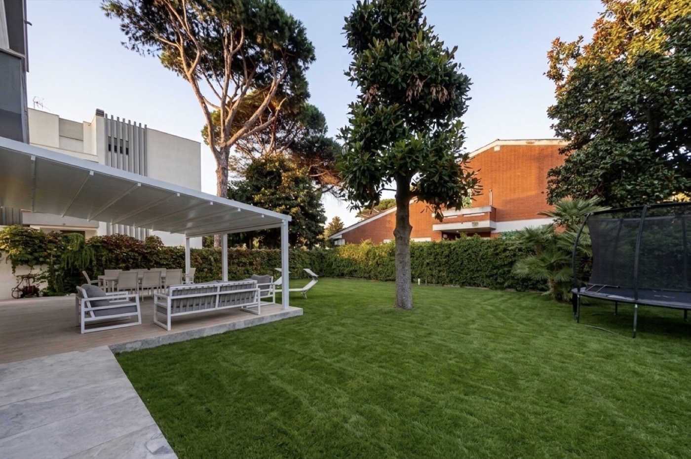 Portico coperto con divani e tavolo, affacciato sul prato del giardino